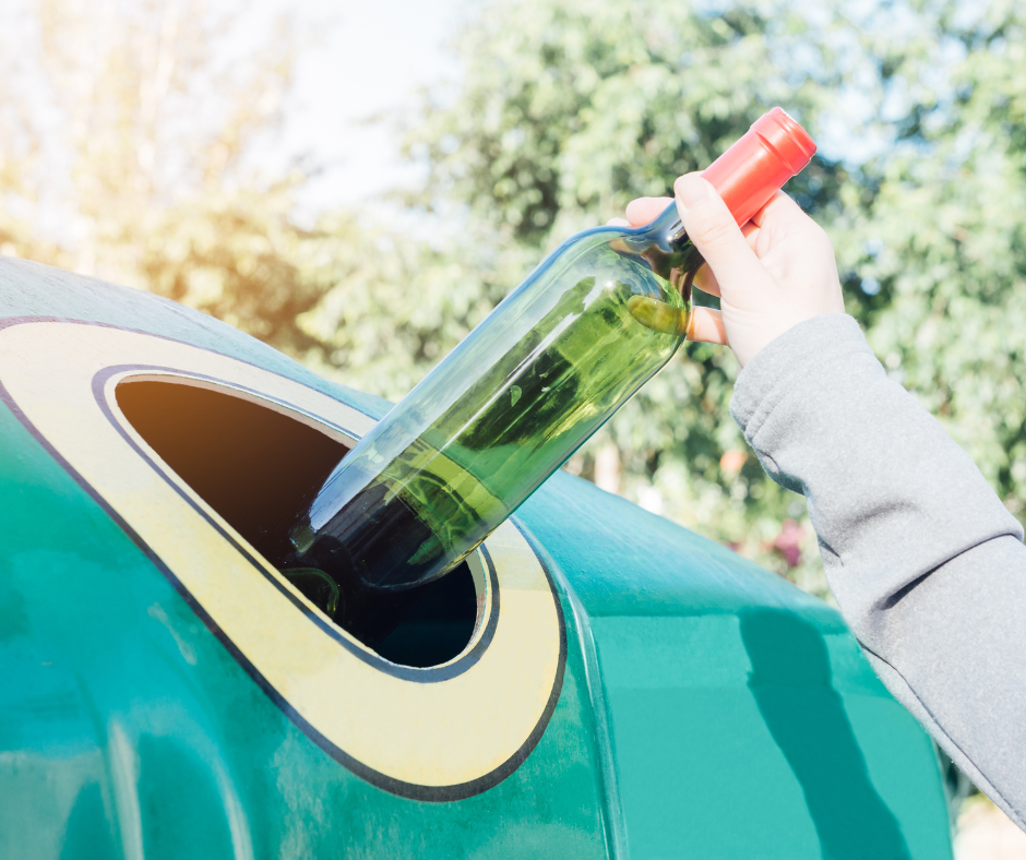 A wine bottle being put into a recycling bank.