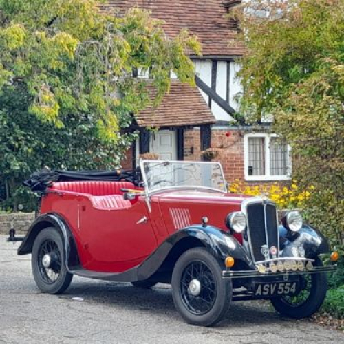 Classic open top car outside an old cottage
