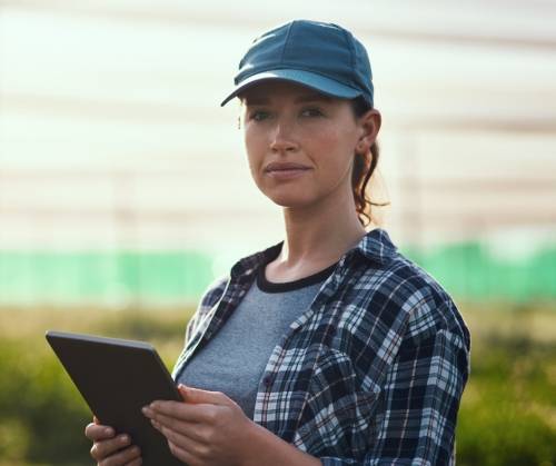 Woman with ipad with crops in the background.