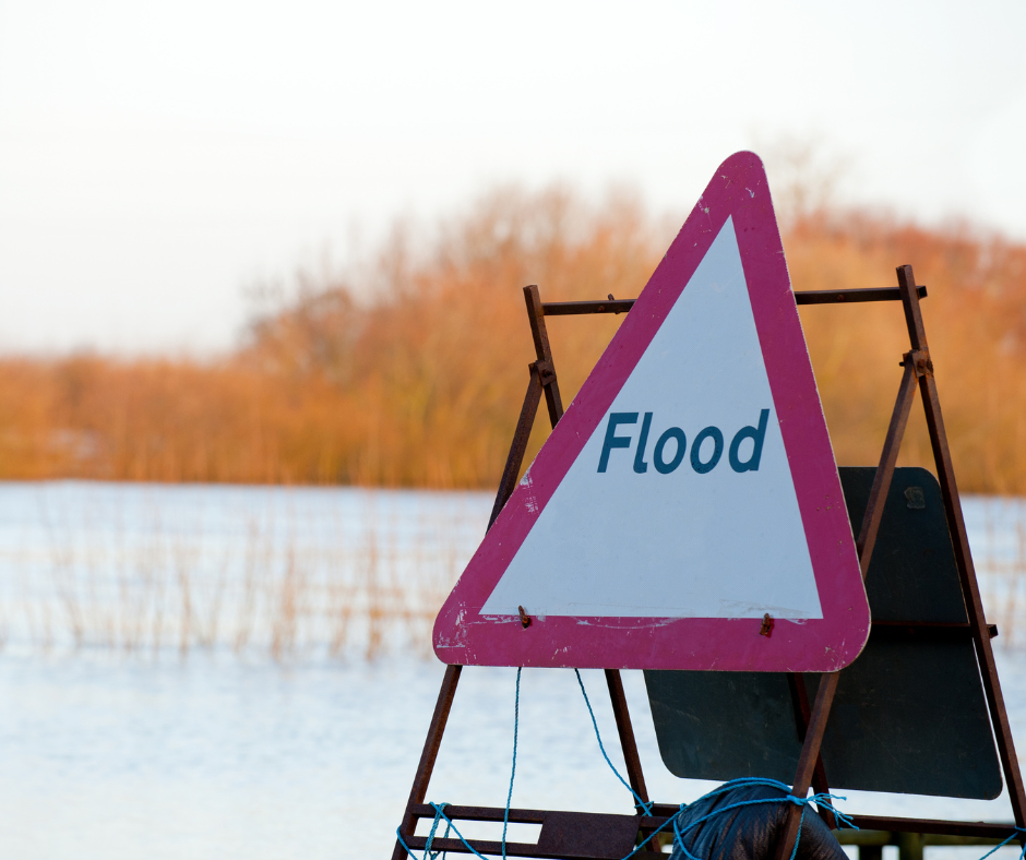 A triangular flood sign with water in background