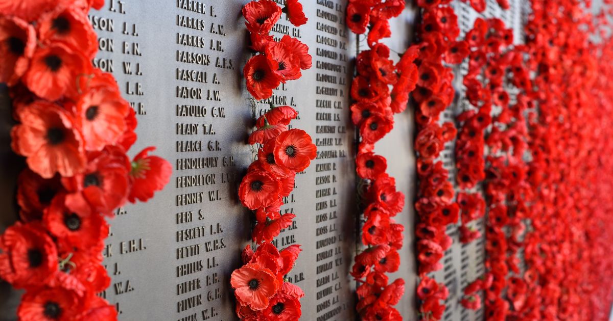 A war memorial is strewn with rows of red poppies of remembrance