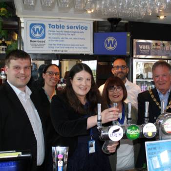 A group of people standing behind a pub bar