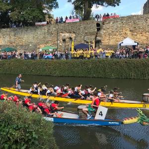 Two dragon boats racing along the river Medway past Tonbridge Castle