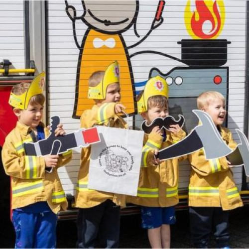 Children dressed up as firefighters in front of a fire engine
