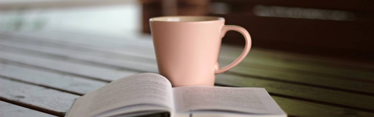 Cup of tea and an open book on a cafe table