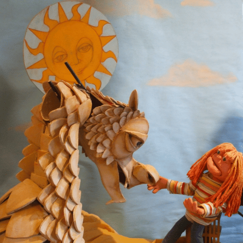 Dragon and child puppet with the sun in the background